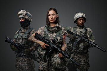 Portrait of team of three army soldiers dressed in camouflage suits holding rifles.