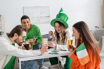 Multiethnic friends celebrating saint patrick day and playing wood blocks game at home