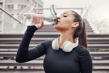 Canvas Print - Workout, hydration and a sports woman drinking water outdoor in the city during cardio or endurance exercise. Runner, fitness and hydrated with a female athlete training in an urban town for health