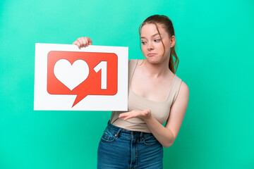 Canvas Print - Young caucasian woman isolated on green background holding a placard with Like icon and pointing it