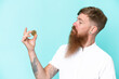 © luismolinero - Redhead man with long beard holding a Bitcoin isolated on blue background with happy expression