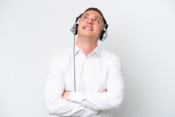 Wall Mural - Telemarketer Brazilian man working with a headset isolated on white background looking up while smiling