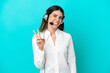 © luismolinero - Telemarketer Italian woman working with a headset isolated on blue background smiling and showing victory sign