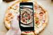 © Sergio - Person photographing pizza on mobile phone camera, close-up. Food photo