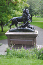 Close Up Of Bronze Lion Sculpture On Stone Plinth In Public Park 