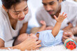 © Tongpool - Mom and father happy joyful playing asian infant baby new born have fun looking to parent face