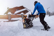 © Sabrewolf - Removing snow from the area using a yellow snow-covered snowblower. Clearing the access road to the house from snowfall.