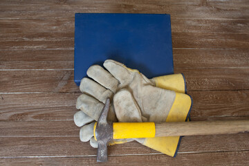 Image of a first aid kit a pair of work gloves and a mason's hammer. Reference to accidents at work.
