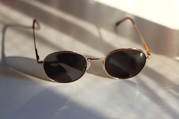 Wall Mural - Retro round sunglasses on the table, illuminated by warm sunlight. Selective focus.