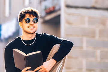 Wall Mural - young man reading with textbook outdoors