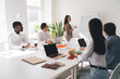 © BullRun - Female speaker showing strategy to multiracial coworkers in conference room