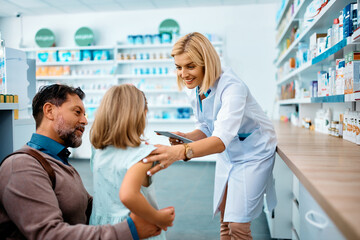 Wall Mural - Happy pharmacist talks to little girl and her father in pharmacy.