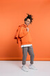 © LIGHTFIELD STUDIOS - full length of positive multiracial man in hoodie holding denim jacket on coral background