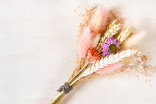 Top View Of Tied Bouquet Of Dried Flowers And Spikelets On Light Brown Wooden Background With Copyspace
