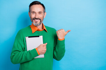 Sticker - Photo of satisfied businessman middle age man brunet hair wear jumper orange shirt tablet finger point empty space isolated on blue color background