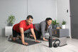 Latino adult couple of man and woman exercise at home taking online class they see the laptop in their living room together they exercise to avoid diabetes and hypertension