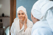 © BASILICOSTUDIO STOCK - Woman in bathrobe applying cream on face in bathroom