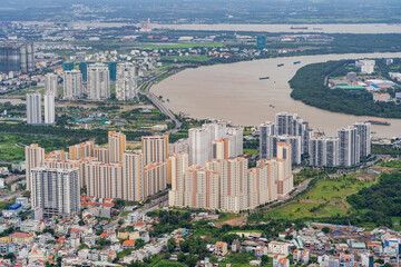 Wall Mural - Aerial view of a high rise city apartment complex alongside a wide river winding through Ho Chi Mihn City in Vietnam