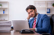 © Elnur - Young male employee and too much work in the office