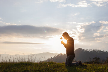 Male Travel holding christian cross praying alone on top mountain sunset background Lifestyle spiritual relaxation emotional concept vacations outdoor harmony with nature landscape