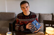 © Cavan Images - young man holding a carefully wrapped Christmas present