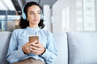 © Rene La/peopleimages.com - Music headphones, phone and business woman on sofa in office streaming audio. Cellphone, technology and thinking female employee on couch listening to podcast, radio or sound with mobile smartphone.