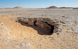Barren rocky desert landscape in hot climate with cave entrance