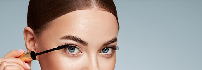 Wall Mural - beauty woman applying black mascara on eyelashes with makeup brush. eyelash extensions. makeup, cosm