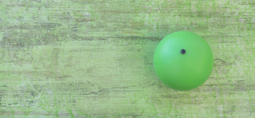 Poster - green plastic ball on a green wooden background