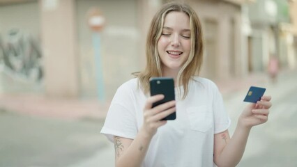 Wall Mural - Young caucasian woman using smartphone and credit card at street