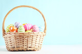 Fototapeta Tulipany - Colorful easter eggs in basket on blue background
