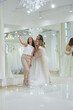 Three girlfriends - A Bride-To-Be and bridesmaids - having fun -Trying On A Wedding Dress