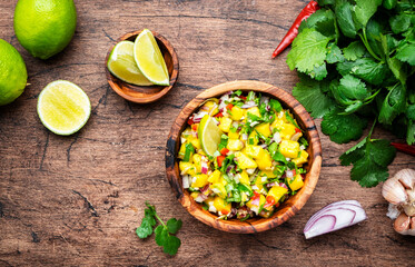 Wall Mural - Spicy mango salsa sauce with red chili peppers, onion, garlic lime and cilantro, rustic wooden table background, top view