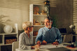 © Zamrznuti tonovi - Senior couple sitting at table and looking into blueprints of their new home