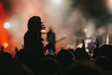 Wall Mural - Silhouette of a woman with raised hands on a concert