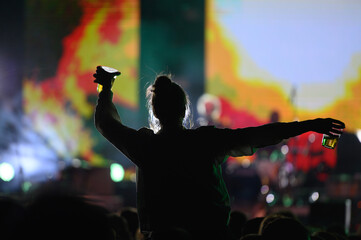 Wall Mural - Silhouette of a woman with raised hands on a concert