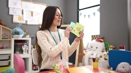 Sticker - Young beautiful hispanic woman preschool teacher teaching vocabulary lesson at kindergarten