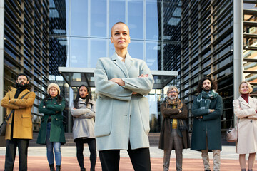 The woman director of the company poses with her team in front of the corporate building. Business people follow the leader to success and female empowerment. High quality photo