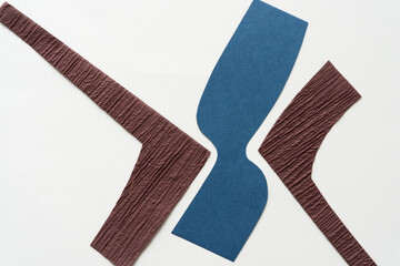 Sticker - two brown and one blue cut paper shapes (corners) on blank paper