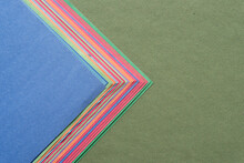 layered construction paper of various colors arranged on rough green paper