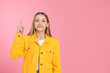 © New Africa - Beautiful teenage girl pointing at something on pink background. Space for text