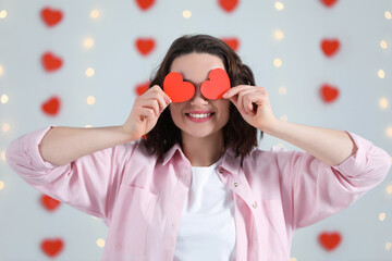 Wall Mural - Beautiful young woman with red paper hearts indoors, view from camera. Valentine's day celebration in long distance relationship