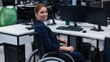 © Михаил Решетников - Caucasian smiling woman in wheelchair at work desk.