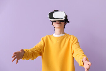 Wall Mural - Teenage boy in VR glasses on lilac background