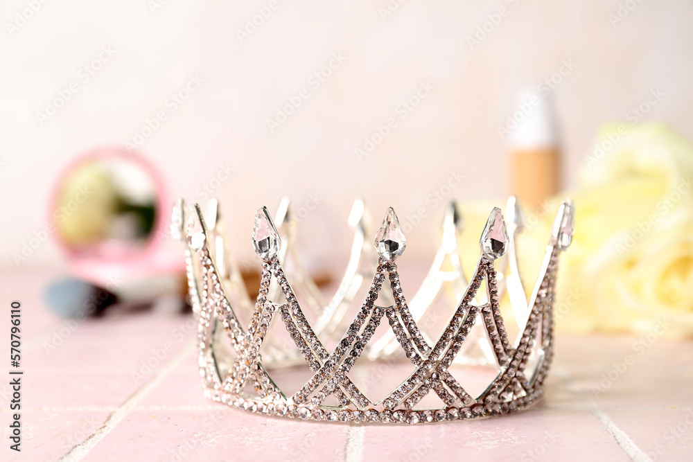 Beautiful tiara on pink tile table, closeup. Prom concept