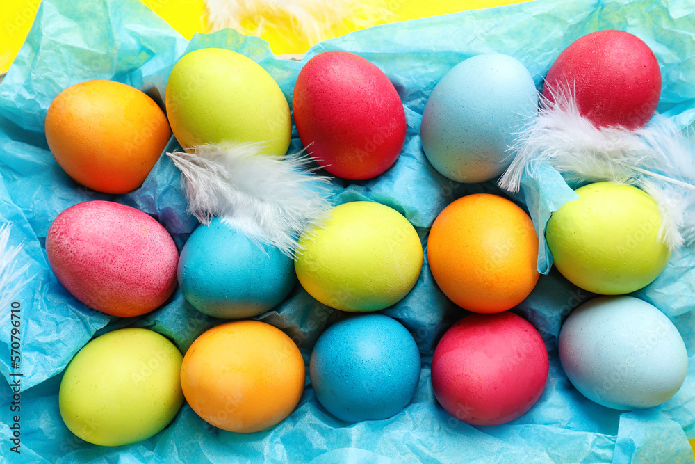 Holder with colorful Easter eggs and feathers, closeup