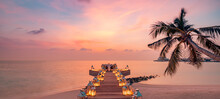 Tranquil Sunset Panorama At Maldives. Luxury Resort Pier Seascape With Candles Lights Under Colorful Sky. Beautiful Romantic Destination Dining Setting Couple Honeymoon, Love Vacation Holiday Panorama