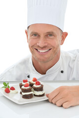 Sticker - Man, face and chef, dessert in portrait and smile, baker skill and cake presentation isolated on white background. Happy person, chocolate and fruit for Valentines day plate and hospitality in studio