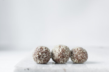 Sticker - Coconut and chocolate truffles on marble tray, homemade chocolate bonbons on white background, desiccated coconut coated truffles