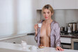 Sensual girl with undressed pajama enjoy coffee. Blond beautiful sexy girl drink morning coffee in kitchen at hame. Morning of pretty sexy woman.